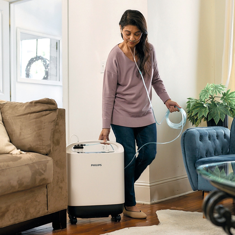 Nainen kävelee olohuoneessa kytkettynä Oxygenate 5 -happirikastimeen.