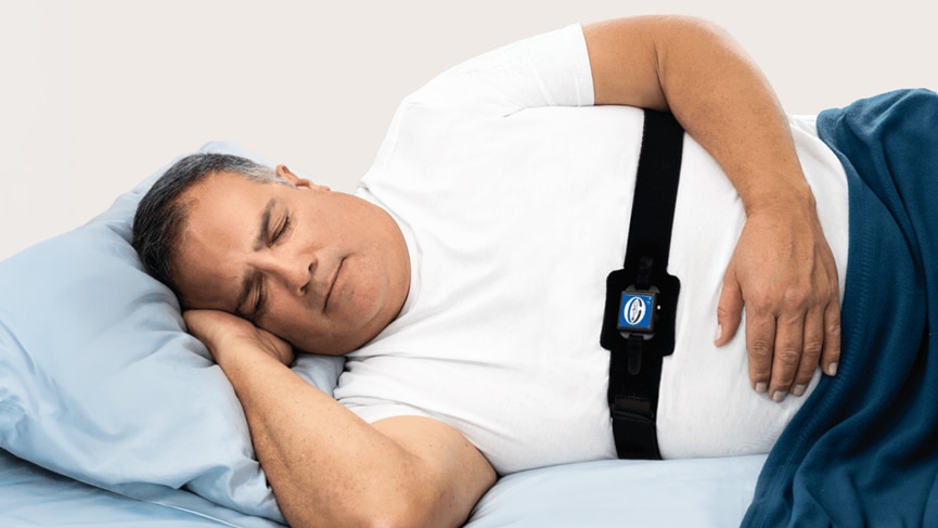 Man sleeping on the side, wearing a belt around his chest with a sleep position trainer.